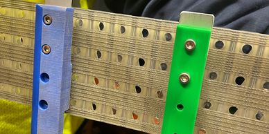 Metal strips with holes and colored plastic brackets.