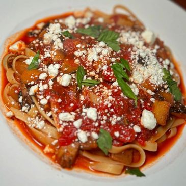 Pasta topped with tomato sauce, crumbled cheese, and fresh basil.