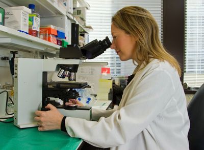 Woman peering through a microscope.