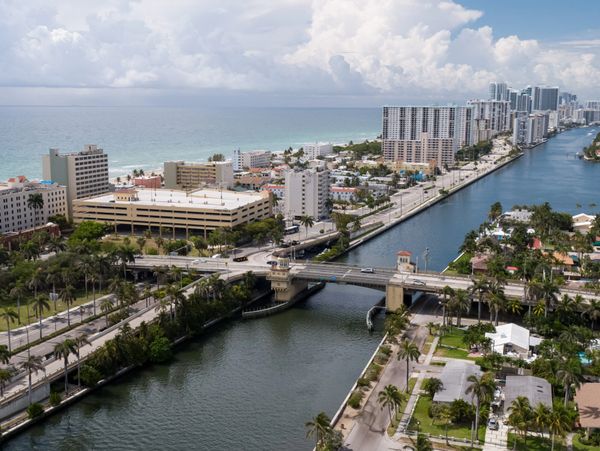 A coastal cityscape with a river, bridge, and high-rise buildings by the ocean.