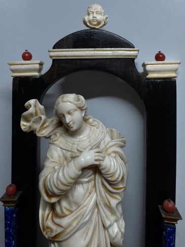 Intricately carved statue of a woman in a decorative frame.