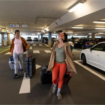 Platinum Transportation Rentals clients walking with luggage through parking garage toward their luxury rental vehicle pickup.