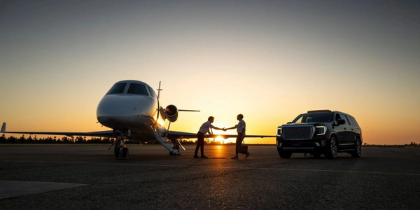 Client being greeted beside private jet with luxury black SUV from Platinum Transportation Group at executive airport.