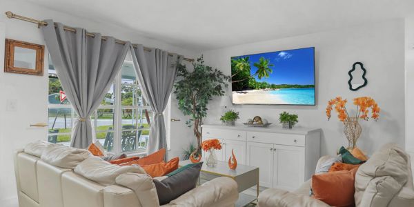 Modern living room with white furniture and tropical decor.