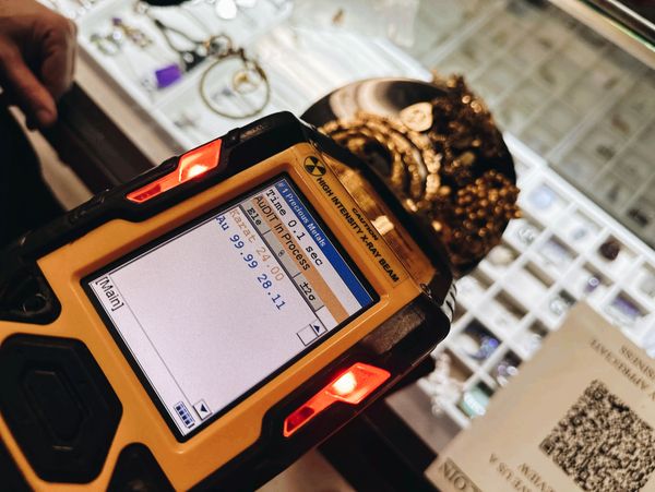 A gold purity tester device analyzing a golden crown with karat and purity details.