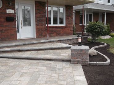 A beautifully designed front entrance with a paved walkway and steps leading to the door.