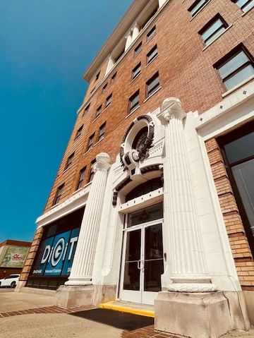 Tall brick building with white columns and a clear blue sky.