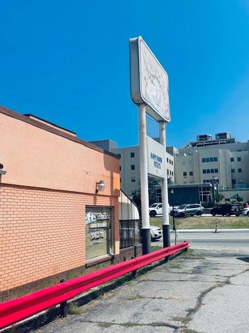 Old motel sign and brick building with red railing under a clear blue sky.