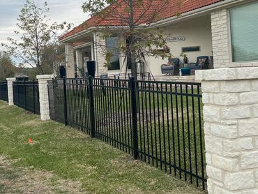A house with a red roof and black metal fence on a cloudy day.