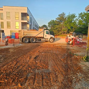 Construction site with dump truck and equipment near a building under development.