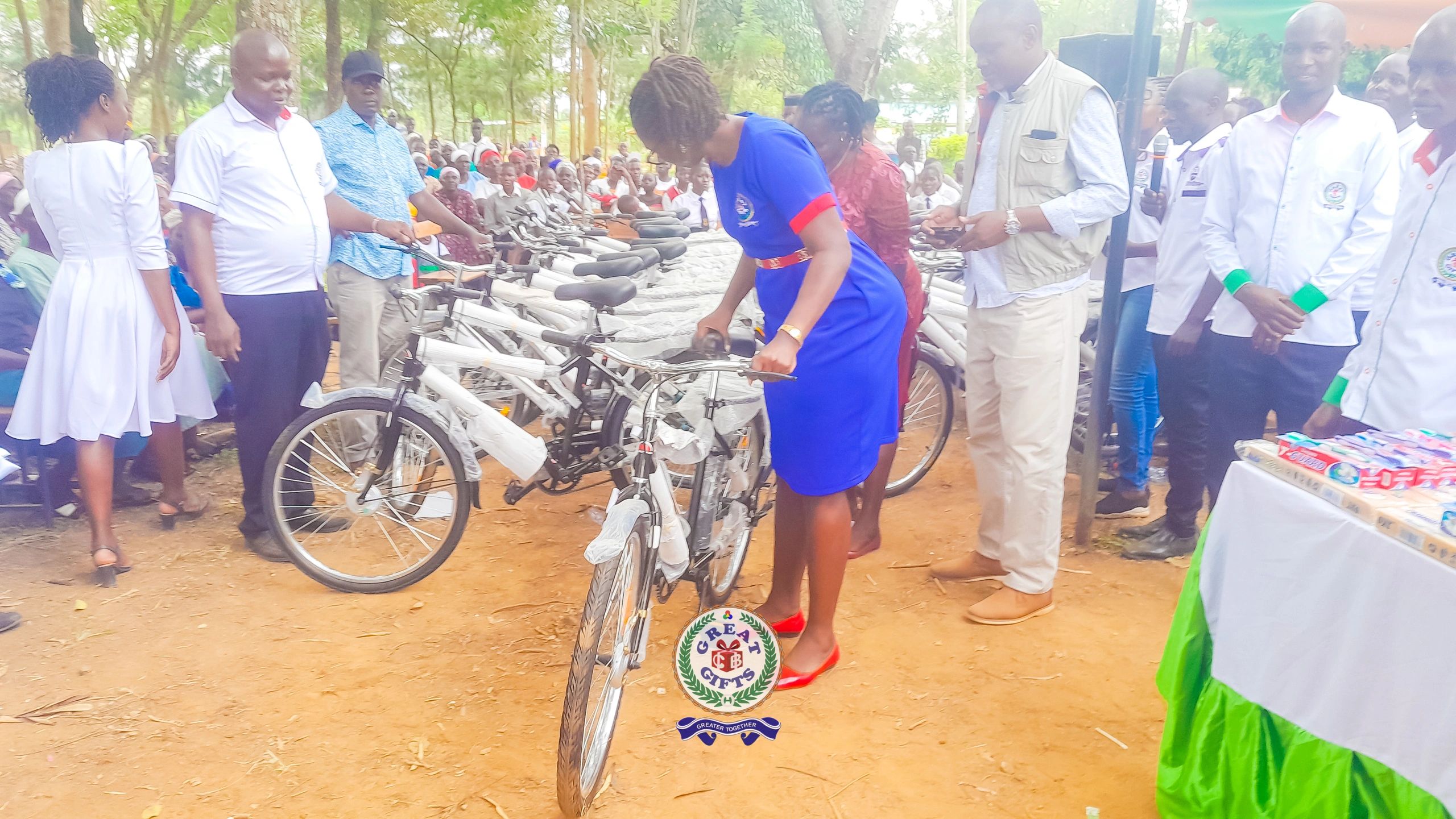 A woman inspects a bicycle during a community event with many bicycles lined up.