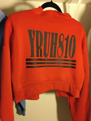 Orange cropped sweatshirt with bold black text and stripes on the back.