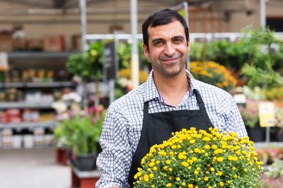 image of a man holding a plant working at a garden center