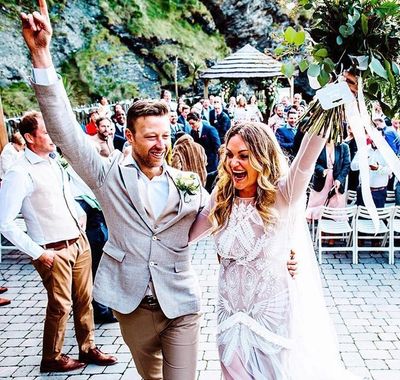 A joyful couple celebrates their wedding outdoors surrounded by guests.