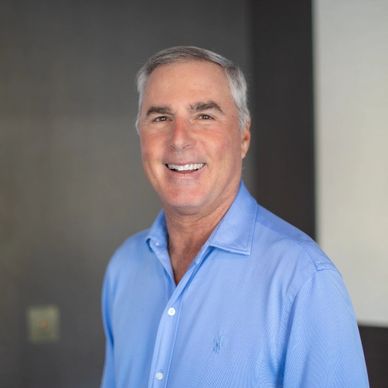 Smiling man wearing a light blue shirt.