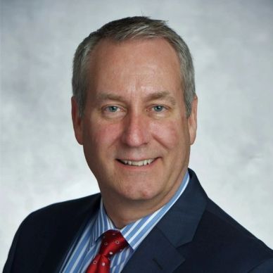 Professional man in suit and red tie smiling.