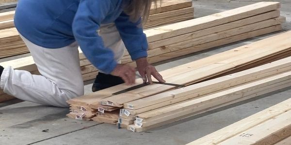 Person measuring wooden planks on the floor.