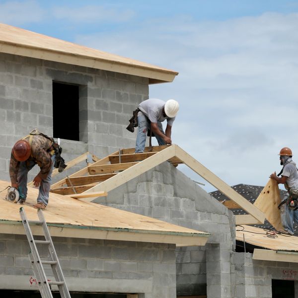 Construction workers building a wooden roof frame on a house.