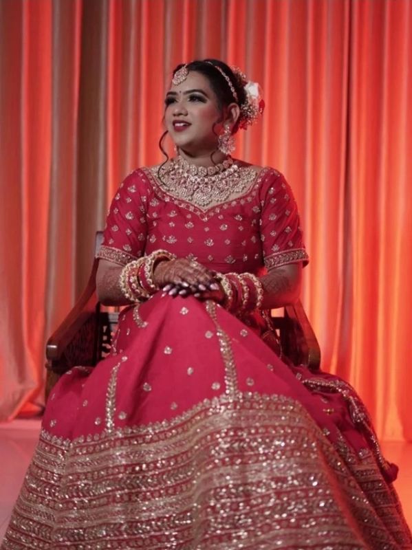 Bride in a red traditional dress sitting on a chair.