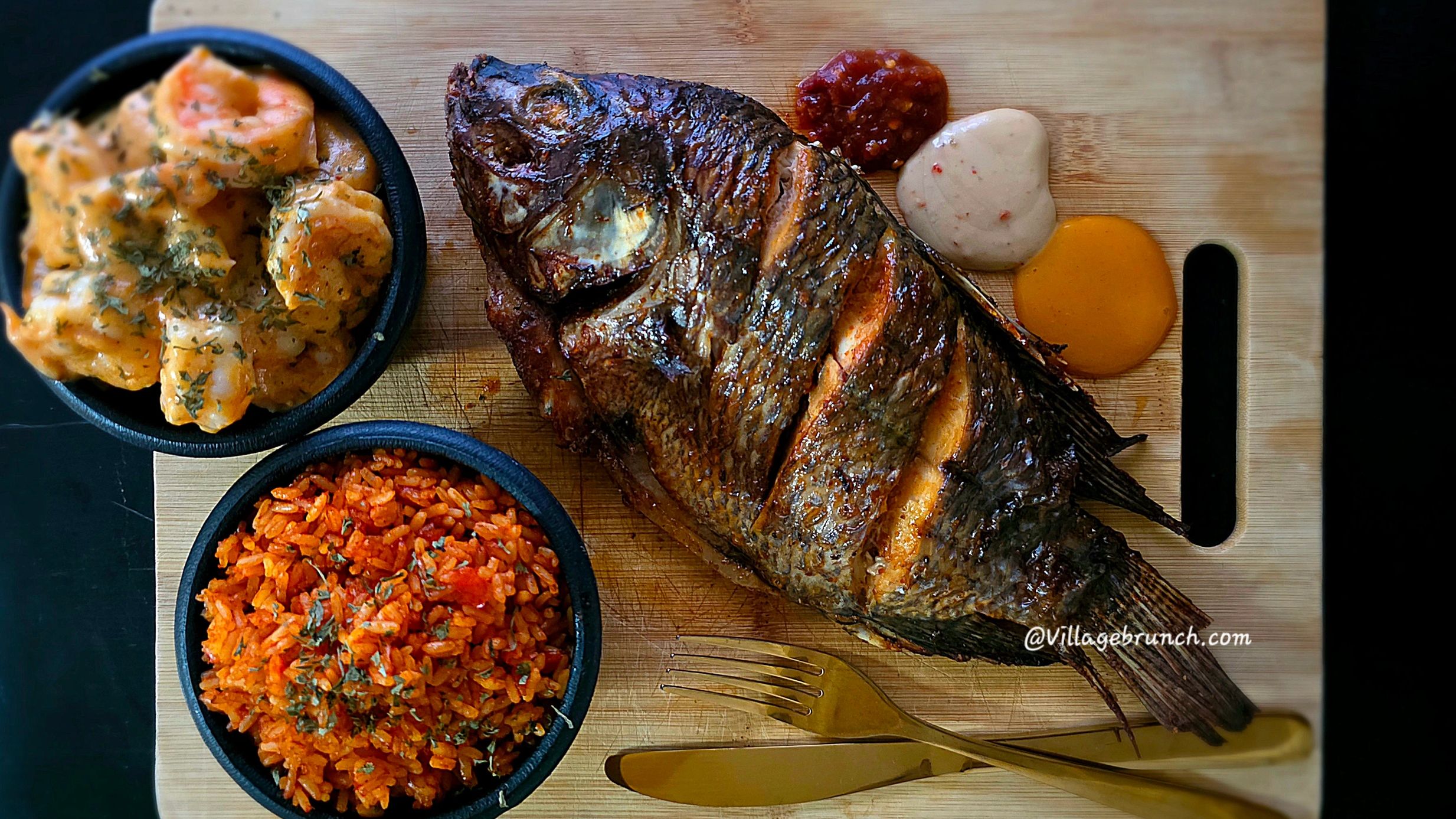 Grilled tilapia, village rice and prawns on chopping board.