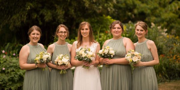 A bride and her bridemaids with their bouquets in garden surroundings.