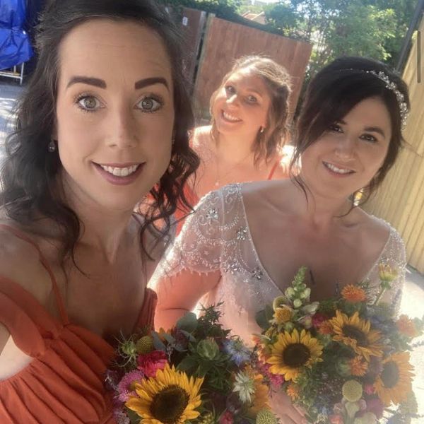 3 ladies smiling with bright bouquets of flowers.