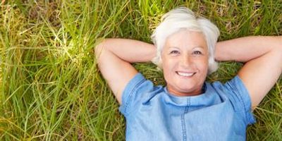 Woman lying on grass smiling, looking confident