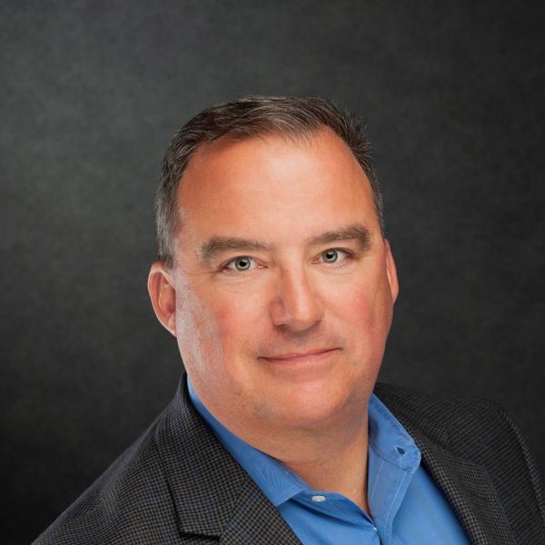 Professional headshot of a confident middle-aged man in business attire.