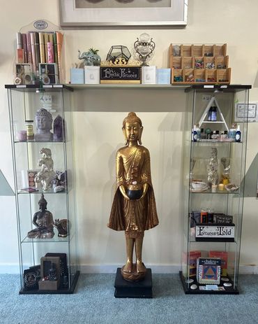 Buddha statue surrounded by incense, crystals, chakra books, essential oils, and chakra bowls.