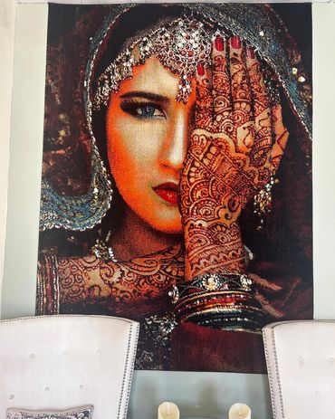 A tapestry of a beautiful woman with henna tattoos on her body. Her left hand is covering one eye.