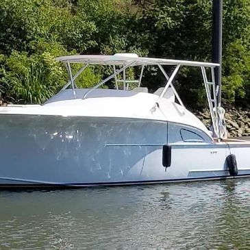 White boat docked near a green shoreline on calm water.