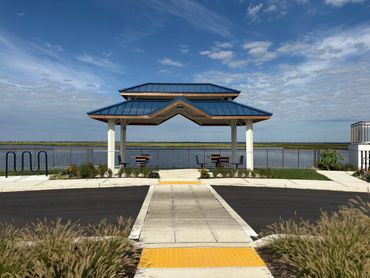 A waterfront gazebo with seating under a blue sky.