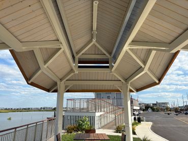View under a wooden pavilion by the water with restrooms and parking nearby.
