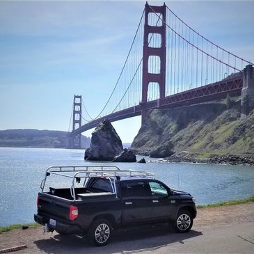 Black pickup truck parked near the Golden Gate Bridge on a sunny day.