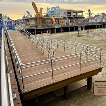 Boardwalk ramp with aluminum railing leading to a seafood pier at sunset.