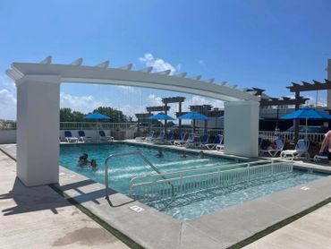 Outdoor swimming pool with water feature and blue umbrellas on a sunny day.