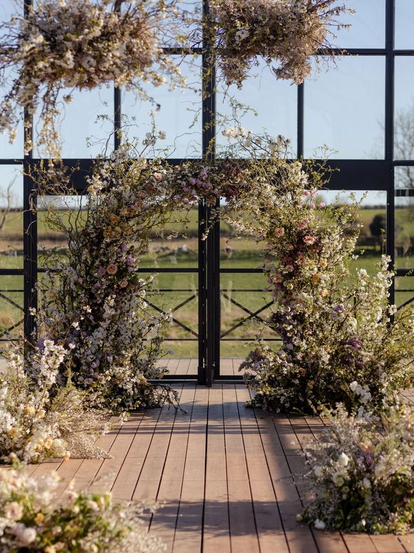 Floral archway with spring flowers inside a glass structure.