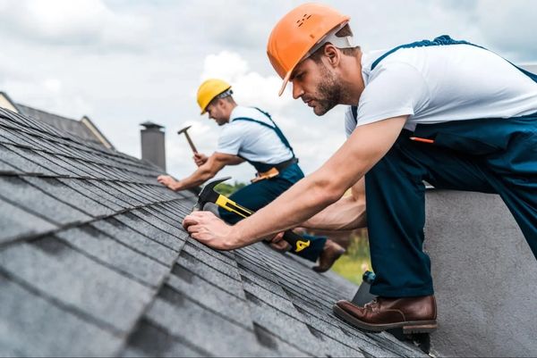 Two Roofing workers repairing a roof.