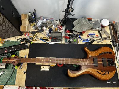 Guitare basse sur un bureau rempli d'outils.