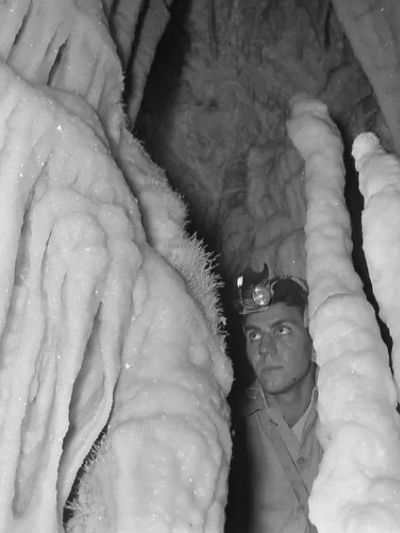 Explorer with headlamp inside an ice-covered cave.