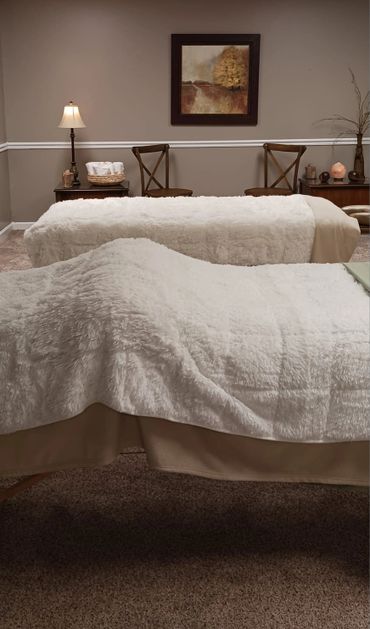 Cozy spa room with two massage tables and warm lighting.