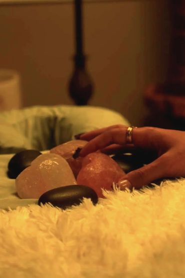 Hand touching smooth massage stones on a soft surface.