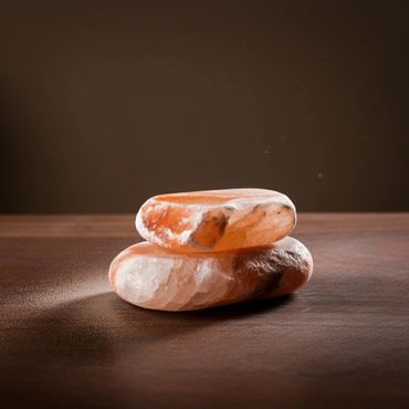Two smooth Himalayan salt stones stacked on a wooden surface.