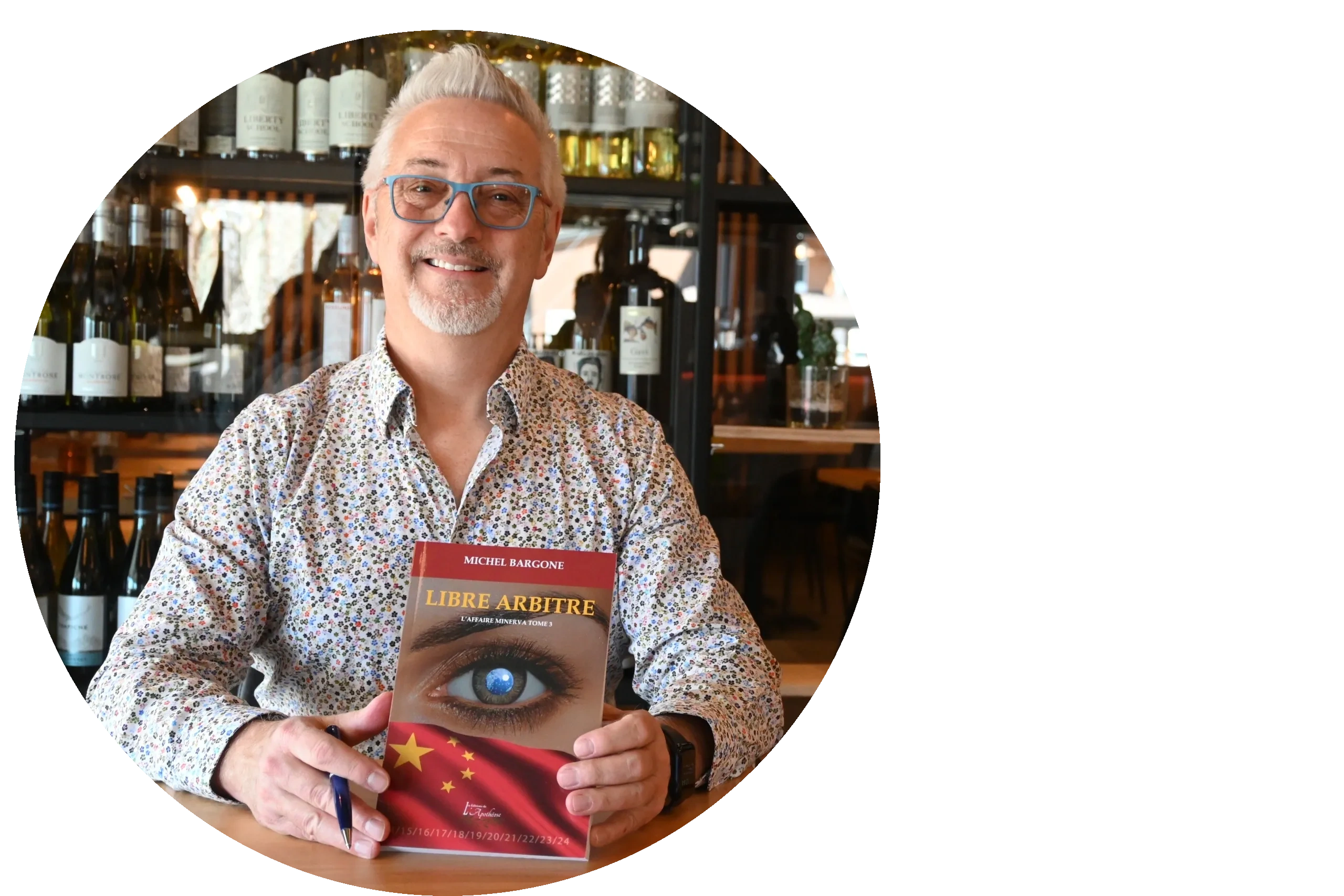 Michel with glasses holding a book titled 'Libre Arbitre' in a cozy setting.