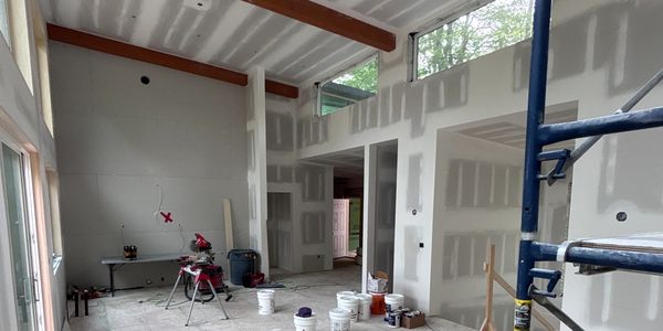 Interior of a room under construction with drywall and construction tools.