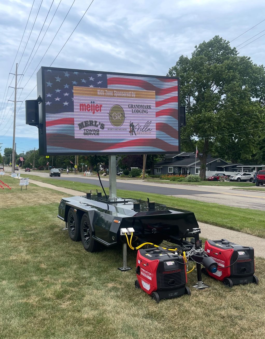 Mobile digital billboard with sponsors' logos on a suburban street.