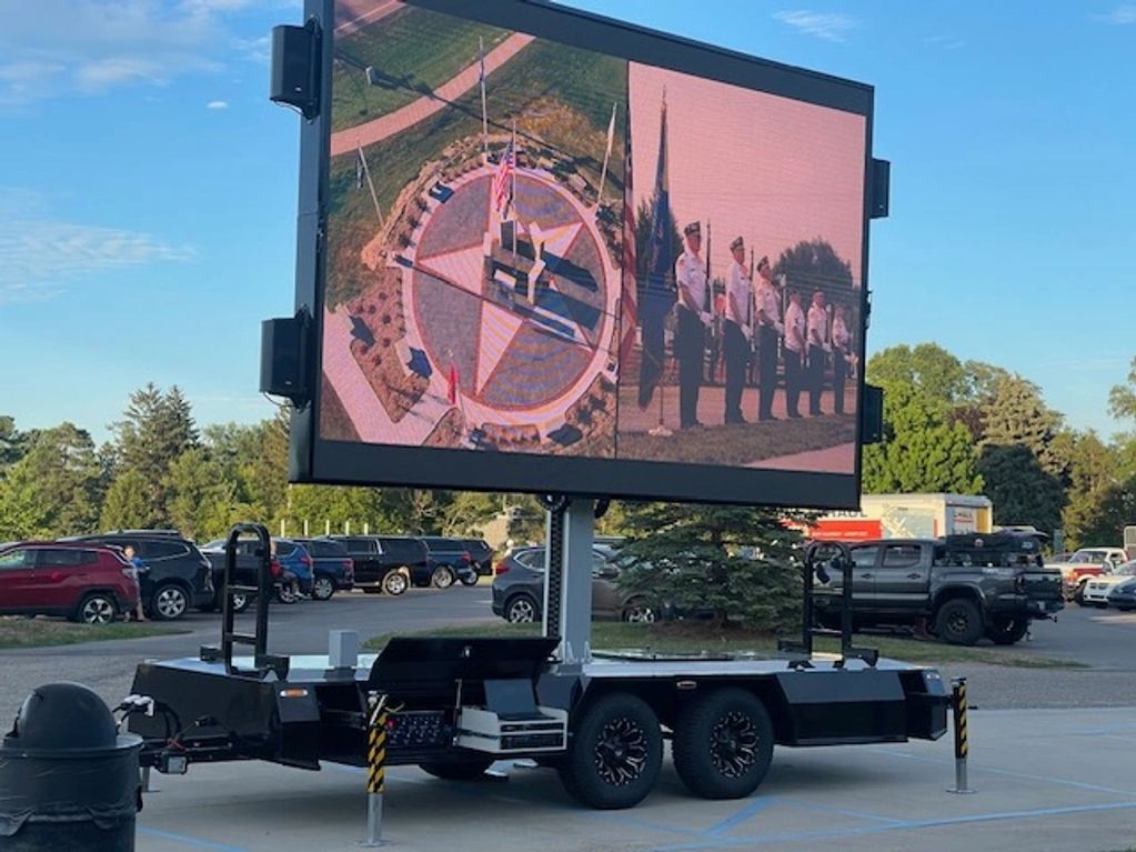 Large outdoor screen on a trailer showing patriotic images.