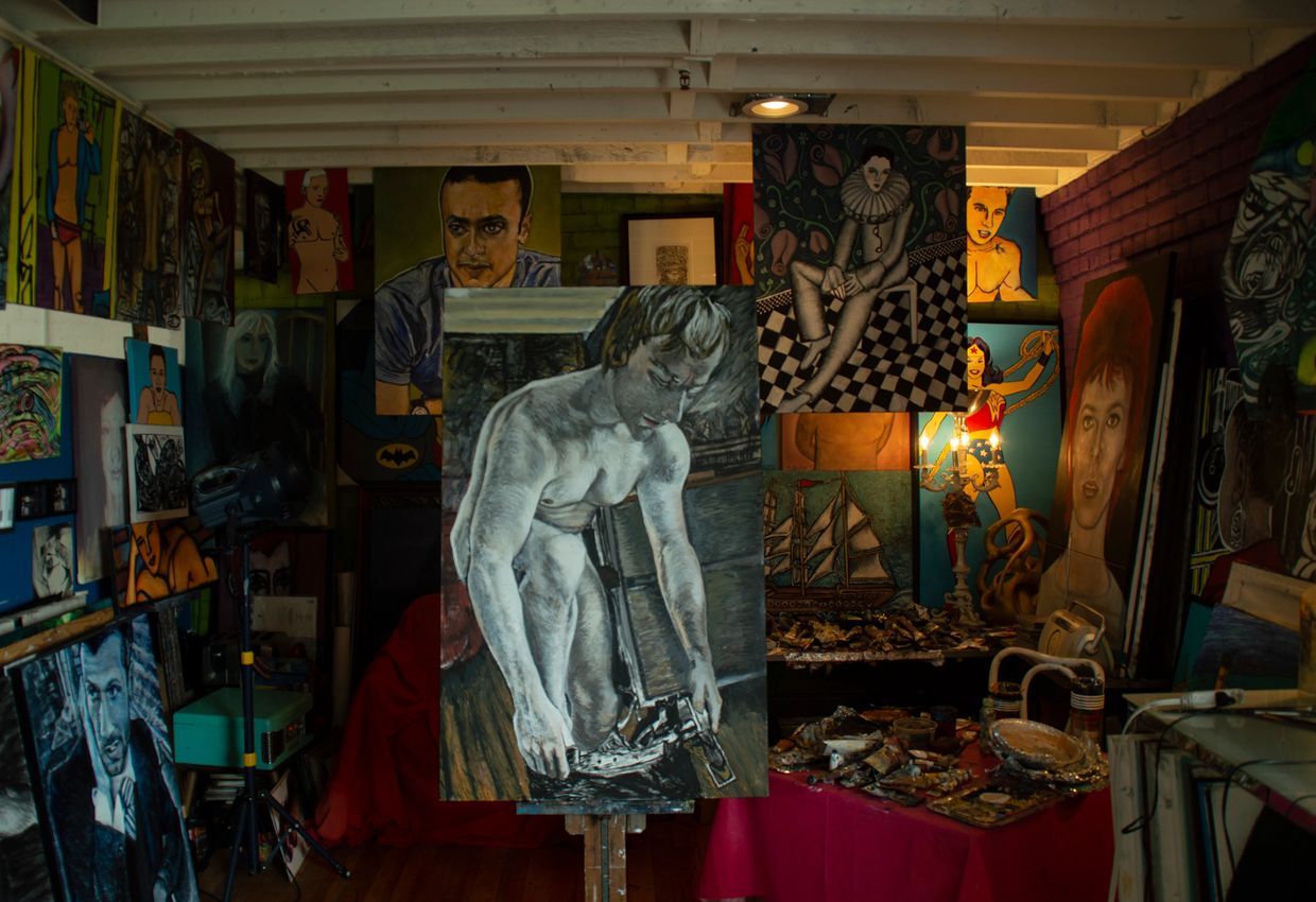 Art studio filled with numerous paintings, including a large monochrome