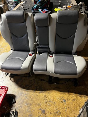 Two-tone car seats on a workshop floor.