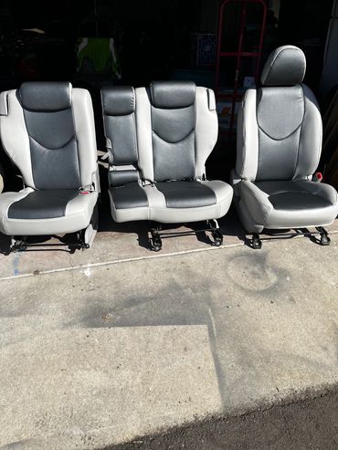 Three gray car seats placed outside on concrete.